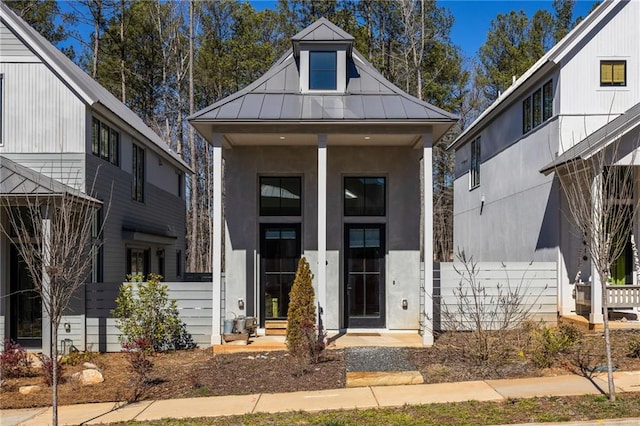 view of front of property featuring a standing seam roof, fence, metal roof, and stucco siding