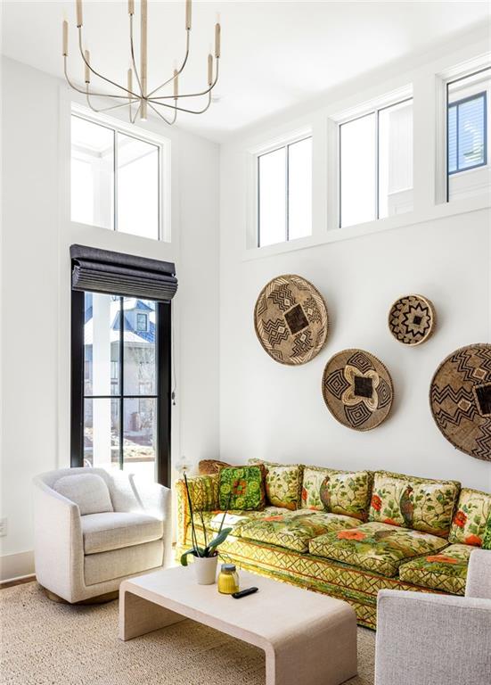 living area featuring a chandelier, a wealth of natural light, and a towering ceiling