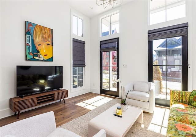 living room featuring baseboards, a high ceiling, and wood finished floors