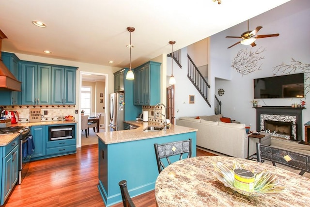 kitchen with appliances with stainless steel finishes, light countertops, a sink, and open floor plan