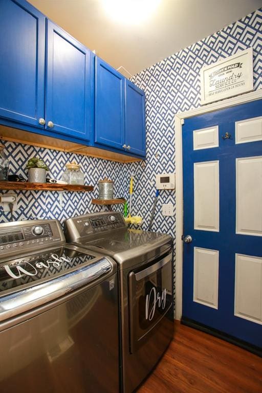 laundry area with dark wood-type flooring, washing machine and dryer, and cabinet space