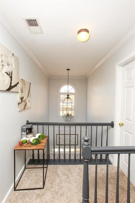 corridor featuring ornamental molding, visible vents, a notable chandelier, and baseboards