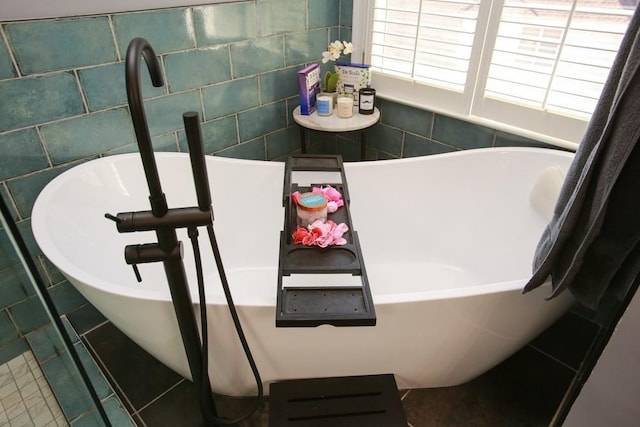 full bath featuring tile walls, a freestanding bath, and tile patterned floors