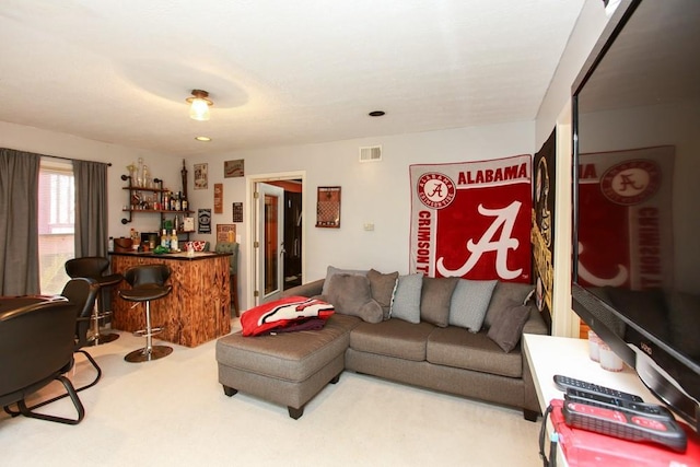 carpeted living area with a dry bar and visible vents