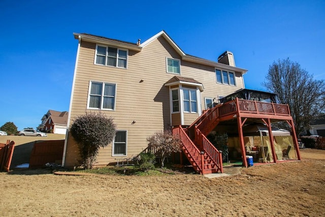 back of house with stairway, a chimney, a wooden deck, and fence