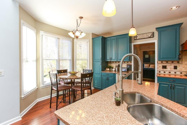 kitchen featuring dark wood finished floors, a sink, decorative light fixtures, and decorative backsplash