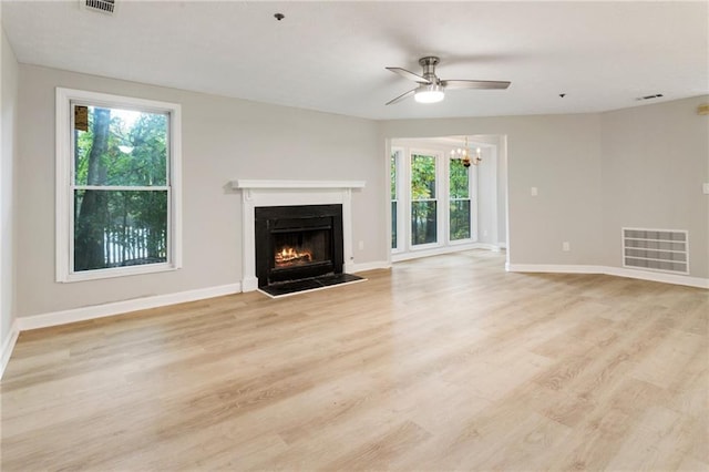 unfurnished living room featuring light wood finished floors, a fireplace with flush hearth, visible vents, and baseboards