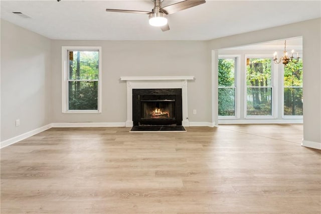 unfurnished living room featuring light wood-style flooring, visible vents, baseboards, and a fireplace with flush hearth