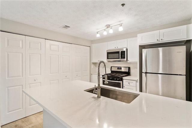 kitchen with stainless steel appliances, light countertops, white cabinetry, and a sink