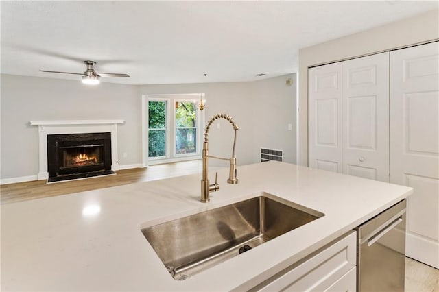 kitchen featuring a sink, white cabinets, open floor plan, light countertops, and stainless steel dishwasher