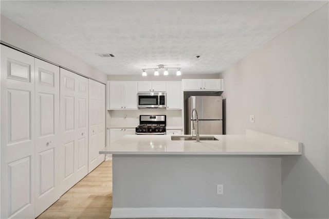 kitchen featuring light countertops, visible vents, appliances with stainless steel finishes, light wood-style floors, and white cabinets