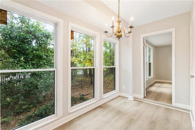 interior space with light wood-type flooring, baseboards, and a notable chandelier