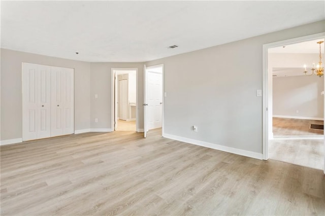 unfurnished bedroom with baseboards, a closet, light wood-style flooring, and a notable chandelier