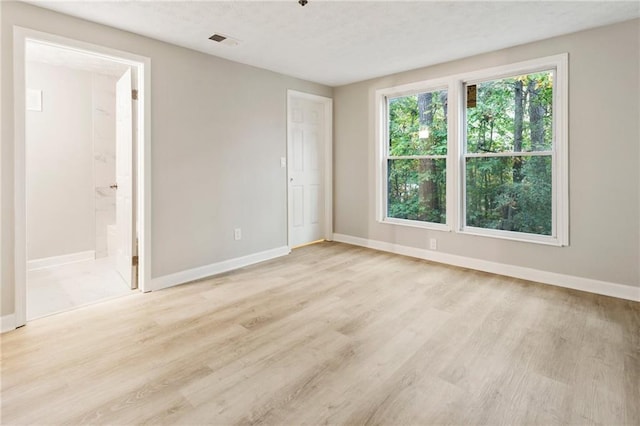 unfurnished room featuring baseboards, visible vents, and light wood finished floors