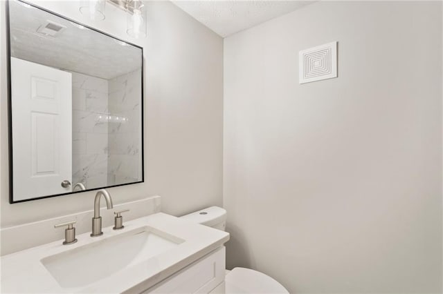 bathroom with visible vents, vanity, toilet, and a textured ceiling