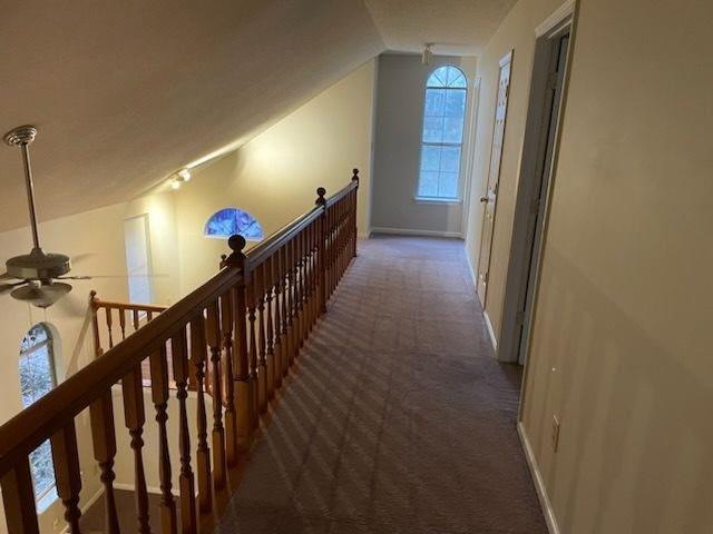 hall with vaulted ceiling, an upstairs landing, carpet, and baseboards