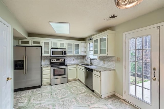 2068 Bedford Ct, Lithonia, GA 30058 - kitchen with visible vents, a sink, backsplash, appliances with stainless steel finishes, and white cabinets