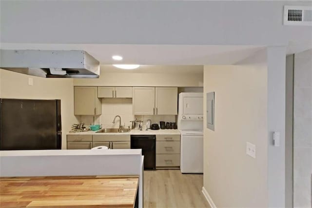 4701 Flat Shoals Rd Unit 50A, Union City, GA 30291 - kitchen with black appliances, estacked washer and dryer, a sink, light wood-type flooring, and exhaust hood