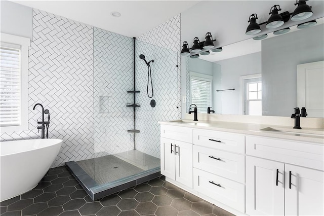 bathroom with tile patterned floors, independent shower and bath, vanity, and tile walls