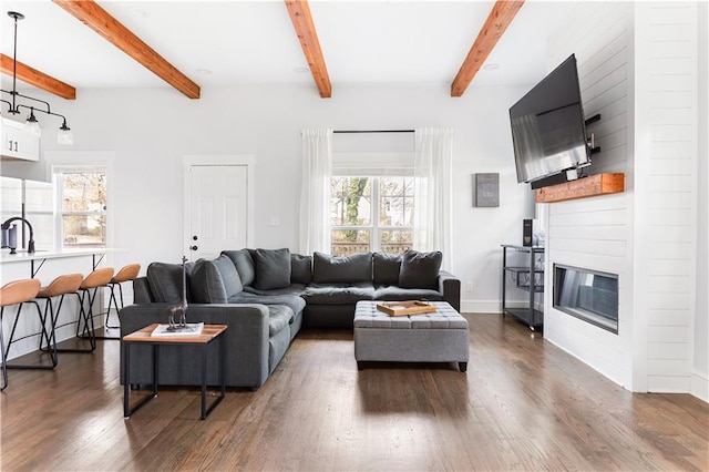 living room featuring dark wood-type flooring, a large fireplace, sink, and beamed ceiling