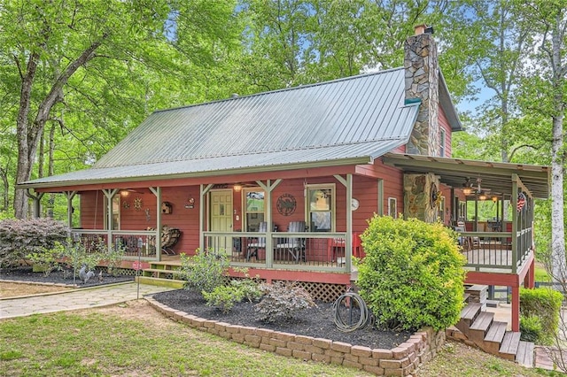 chalet / cabin featuring a chimney, a porch, metal roof, and ceiling fan