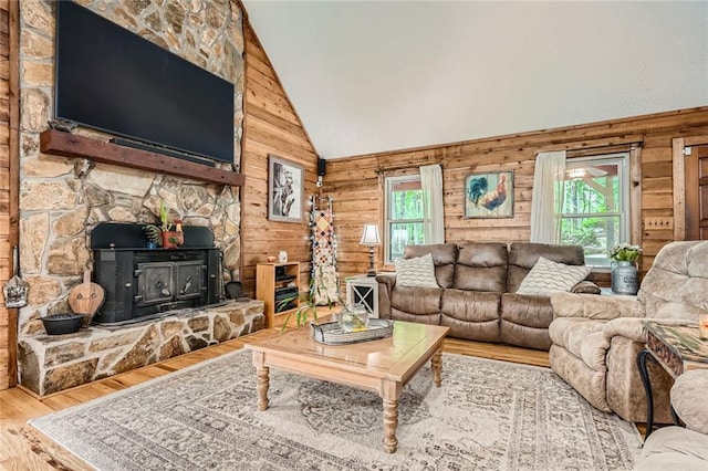 living area with high vaulted ceiling, wood walls, wood finished floors, and a wood stove