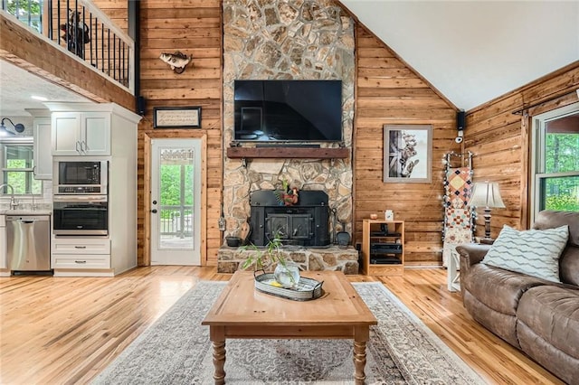 living area featuring light wood-type flooring, wood walls, and high vaulted ceiling