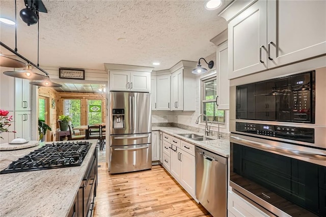 kitchen featuring light wood-type flooring, a sink, black appliances, and a healthy amount of sunlight