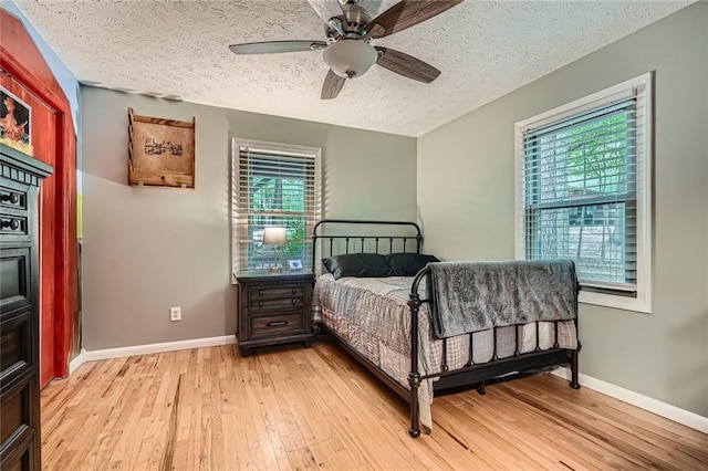 bedroom with a textured ceiling, baseboards, and light wood finished floors