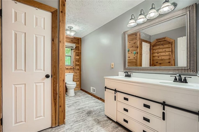 bathroom featuring visible vents, a sink, a textured ceiling, and wood finished floors