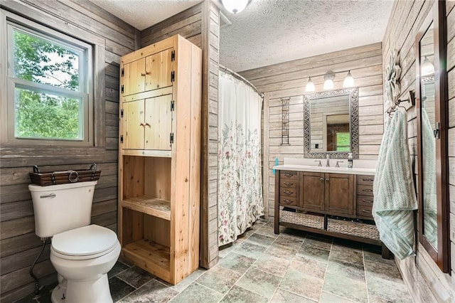 full bathroom featuring vanity, stone tile flooring, toilet, a shower with shower curtain, and wooden walls