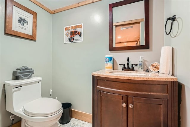 bathroom with vanity, ornamental molding, baseboards, and toilet