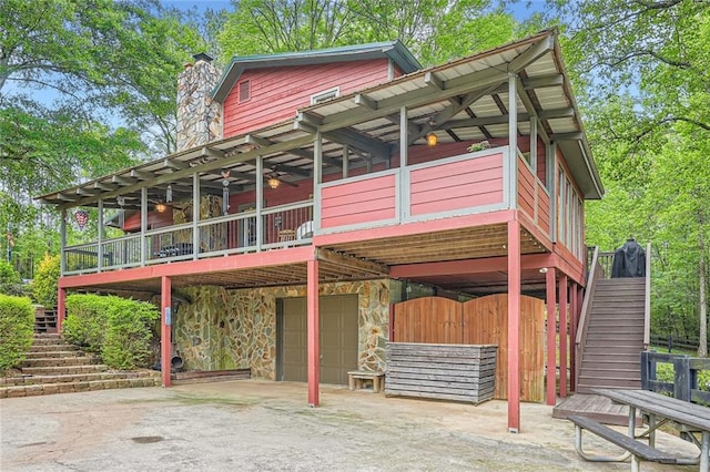 exterior space with an attached garage, a chimney, stairway, and aphalt driveway