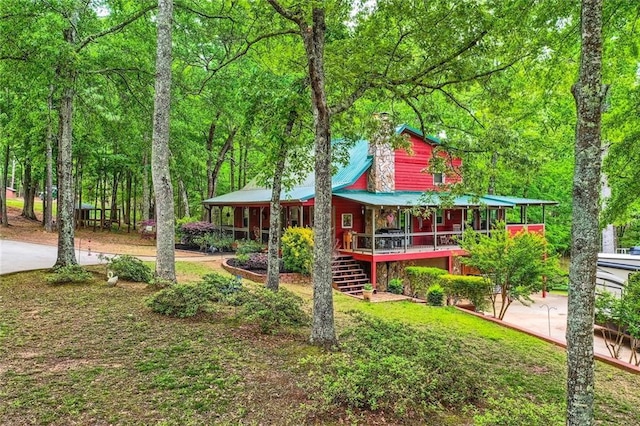 exterior space featuring covered porch, a chimney, and stairs