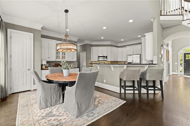3749 Watkins Pl NE, Brookhaven, GA 30319 - dining area featuring a chandelier, arched walkways, recessed lighting, crown molding, and dark wood-type flooring
