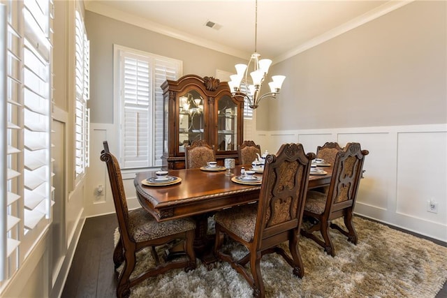 dining area featuring a wainscoted wall, visible vents, wood finished floors, crown molding, and a decorative wall