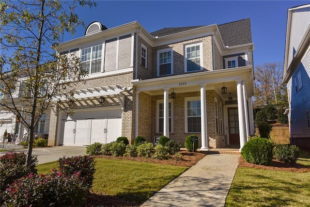traditional-style house with a front lawn, driveway, a porch, brick siding, and a garage