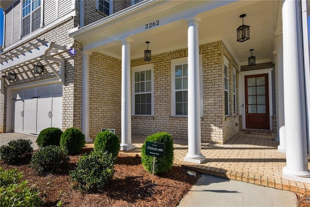 property entrance with brick siding, a porch, and a garage
