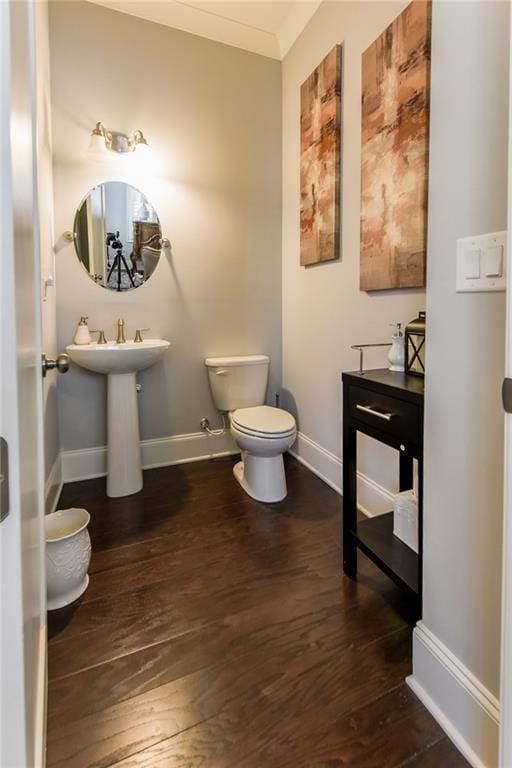 half bathroom featuring wood finished floors, toilet, and baseboards