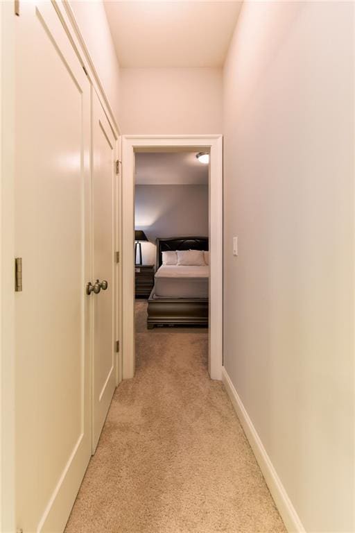 hallway featuring light carpet and baseboards