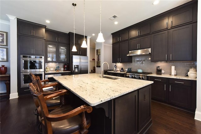 kitchen featuring under cabinet range hood, visible vents, a sink, decorative backsplash, and appliances with stainless steel finishes