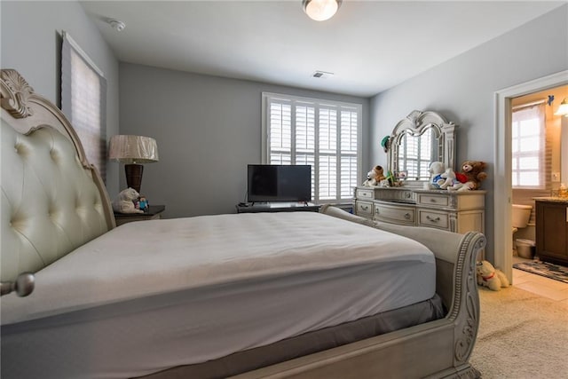 carpeted bedroom featuring ensuite bathroom and visible vents