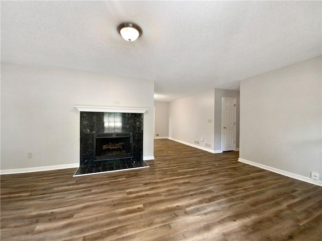 unfurnished living room with baseboards, wood finished floors, and a tiled fireplace