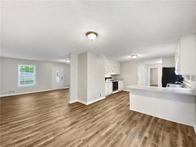 kitchen featuring wood finished floors, a sink, white cabinets, white gas range oven, and black fridge