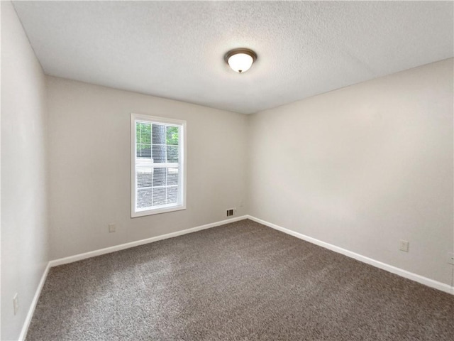 unfurnished room featuring visible vents, dark colored carpet, and baseboards