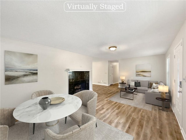 dining area featuring baseboards, a textured ceiling, wood finished floors, and a fireplace