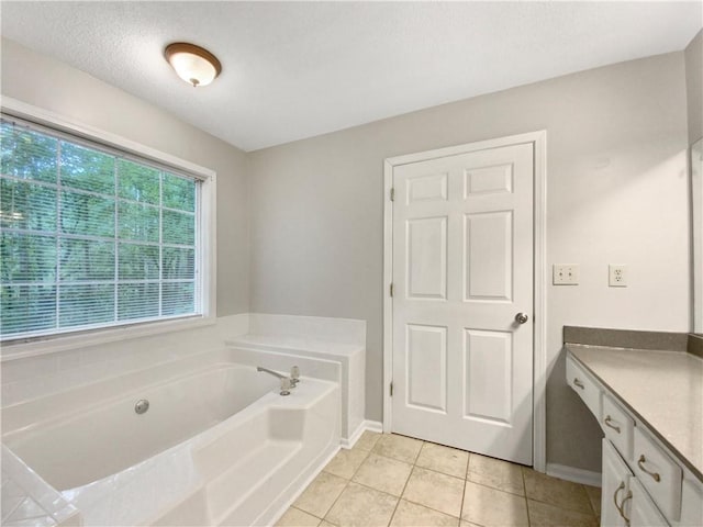 full bath featuring baseboards, a bath, vanity, and tile patterned flooring