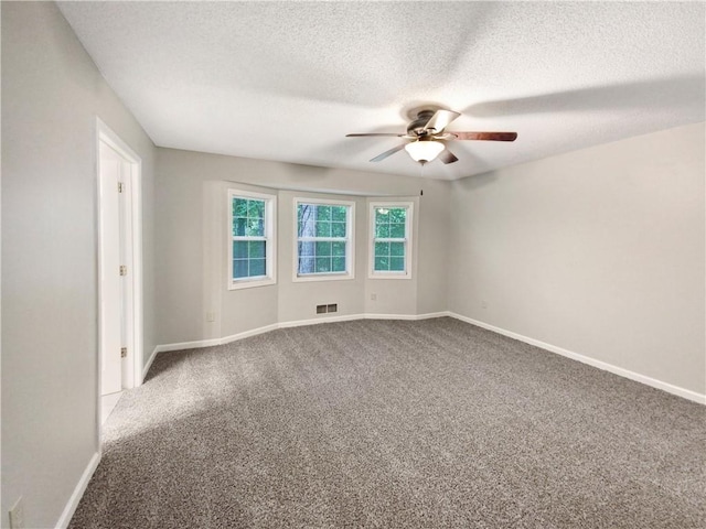 carpeted spare room with visible vents, a textured ceiling, a ceiling fan, and baseboards