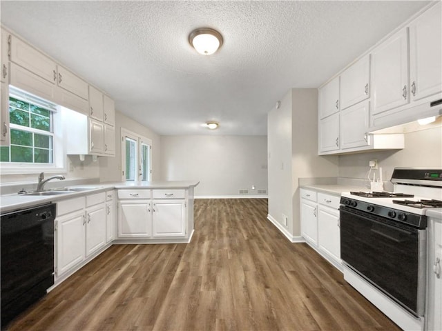 kitchen featuring a peninsula, a sink, black dishwasher, white gas range oven, and under cabinet range hood