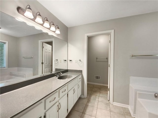 bathroom featuring visible vents, tile patterned flooring, baseboards, a bath, and vanity